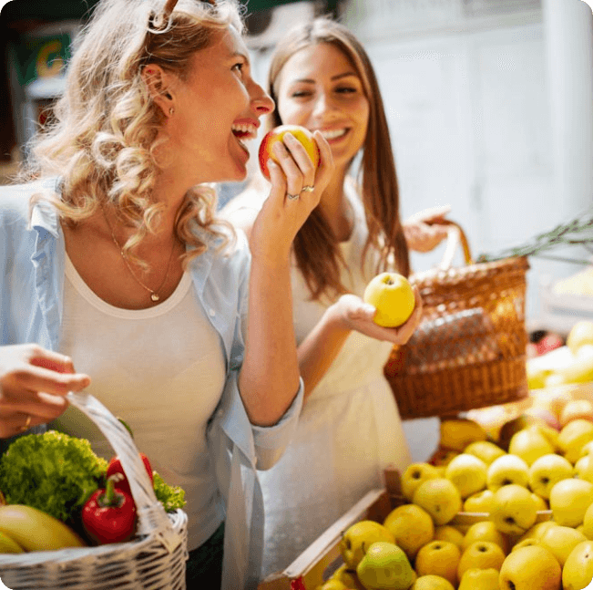 Zwei Freundinnen kaufen Äpfel auf Bauernstand