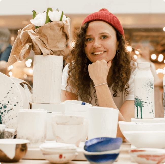 Junge Frau präsentiert auf Marktstand Keramik